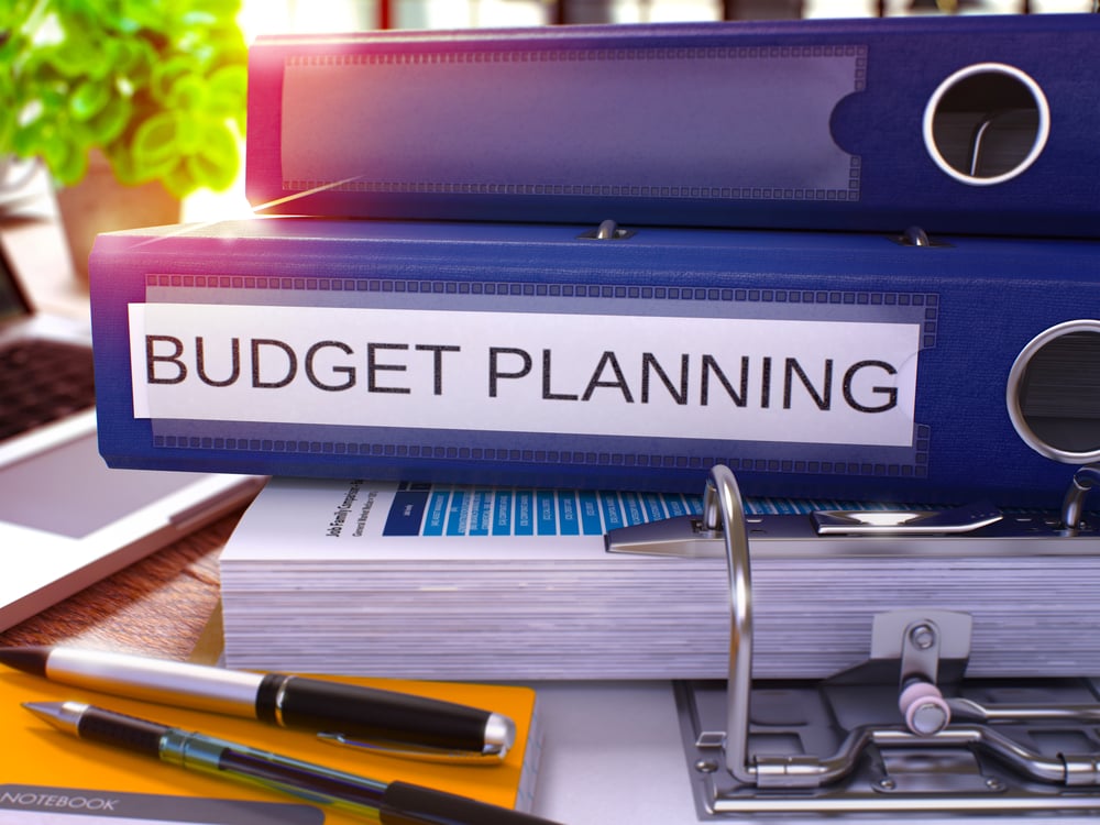 Niebieski segregator z napisem Budget Planning na tle biurka z artykułami biurowymi i laptopem. Biznesowa koncepcja planowania budżetu na rozmytym tle. Render 3D.-1