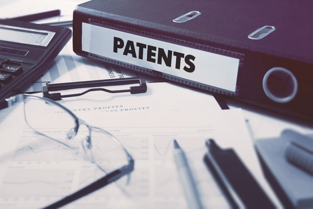 Biurowy segregator z napisem Patents na biurku z artykułami biurowymi. Koncepcja biznesowa na rozmytym tle. Obraz tonowany.